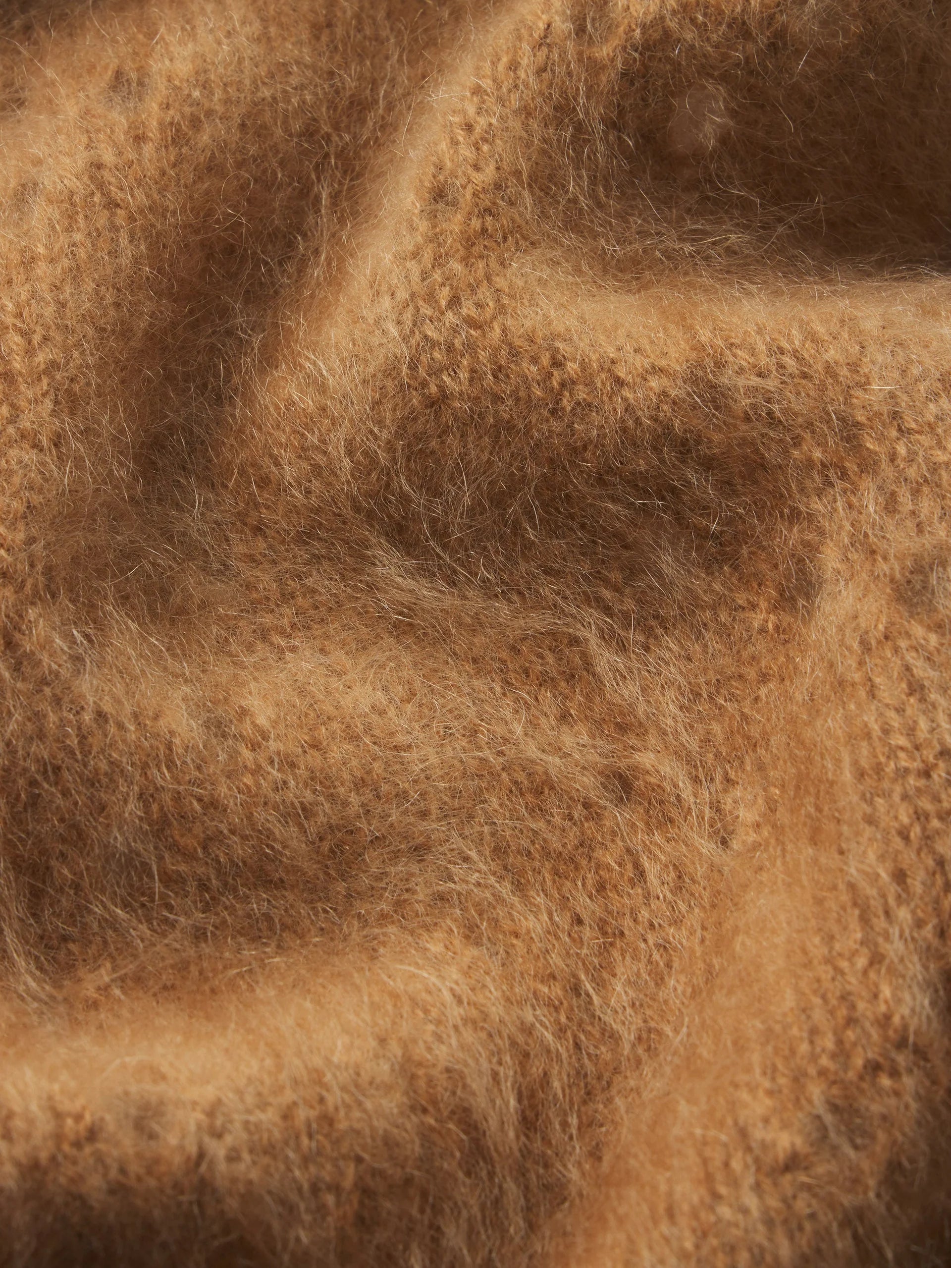 A close-up of a soft, fuzzy brown fabric with a warm camel or tan tone, showing the texture and drape of the material.