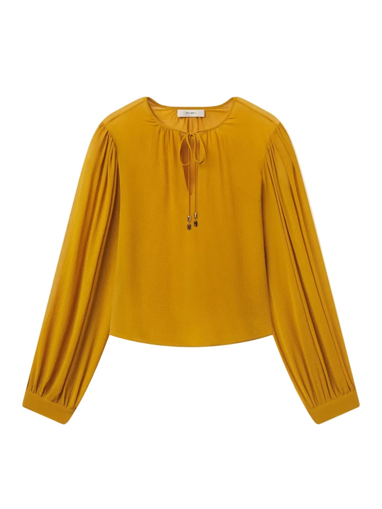 A mustard yellow long-sleeve blouse with a round neckline, front tie detail, and gathered sleeves, shown flat on a light gray background.