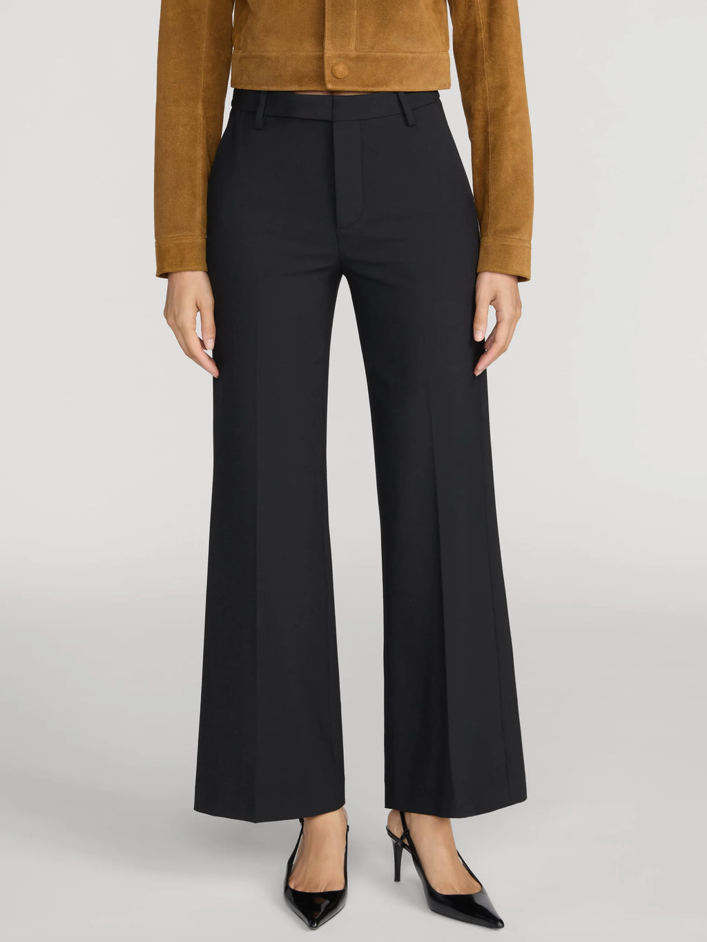 A model is shown from the waist down wearing black wide-leg cropped trousers, a brown suede cropped jacket, and black pointed-toe heels against a light gray studio background.