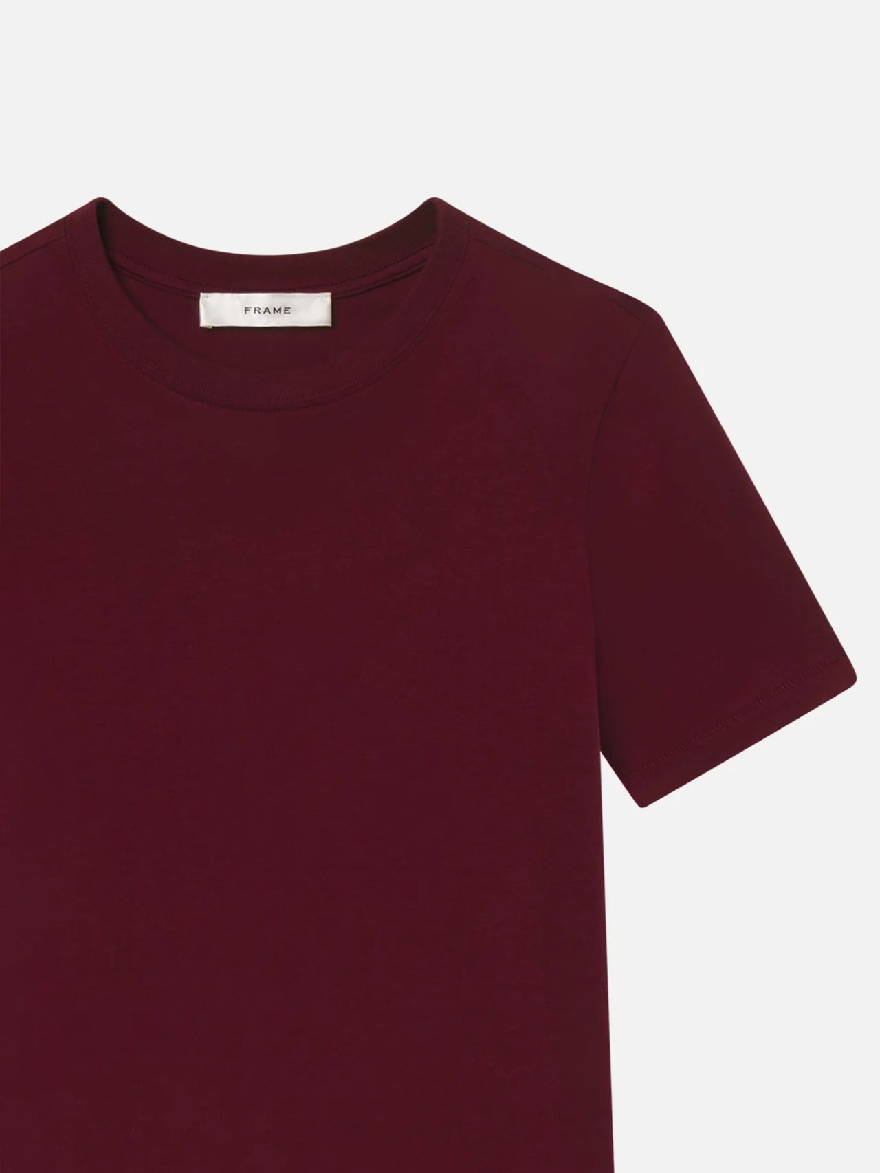 Maroon t-shirt with a brand label on a light gray background