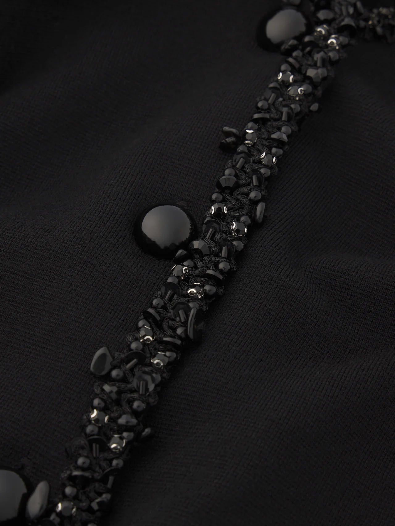 Close-up of a black bracelet with silver stones on a dark background