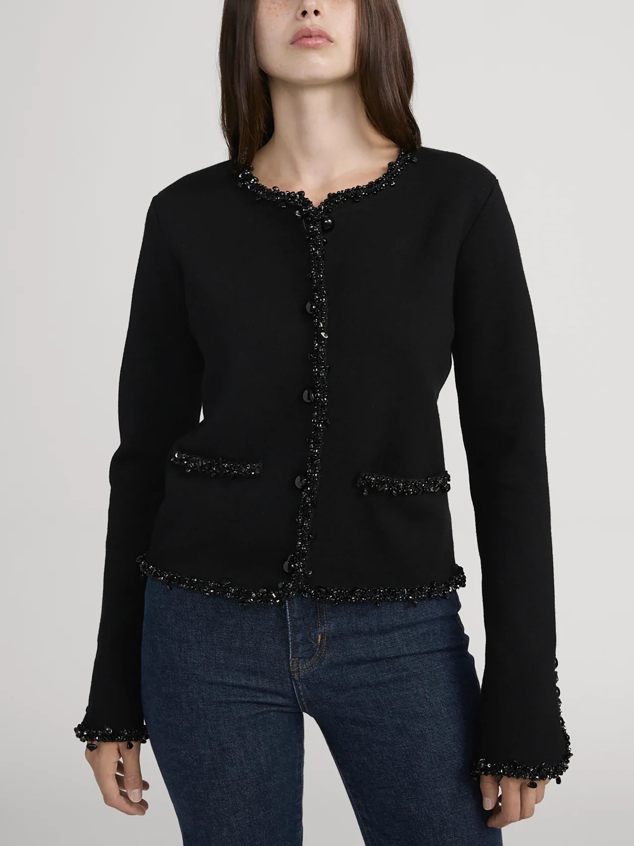 Black embellished jacket worn by a model on a plain background