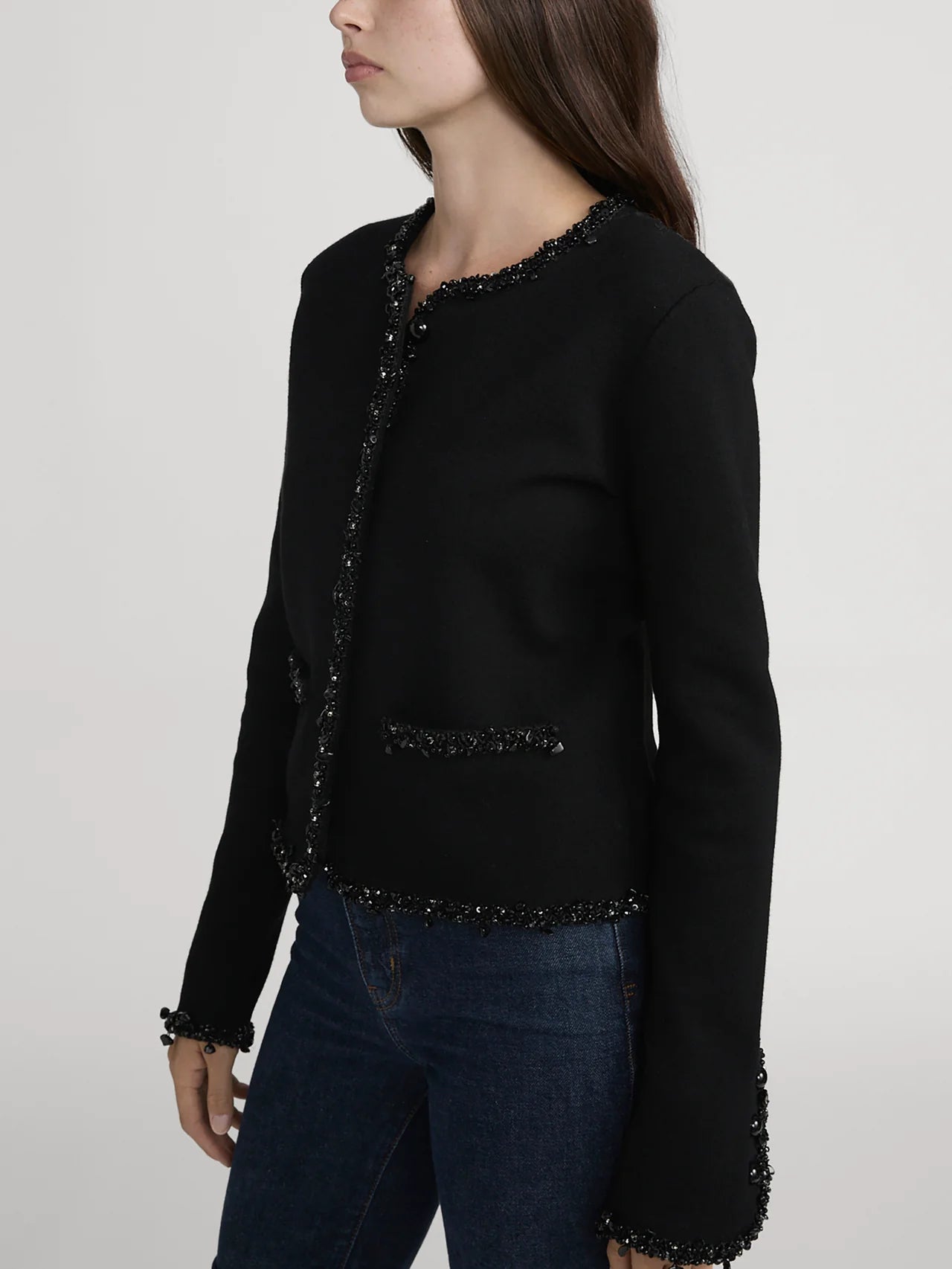 Black beaded jacket worn by a person on a plain background