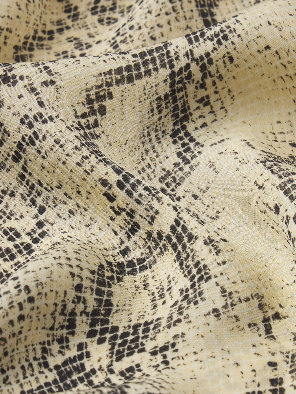 Close-up of fabric with black snake skin pattern on beige background