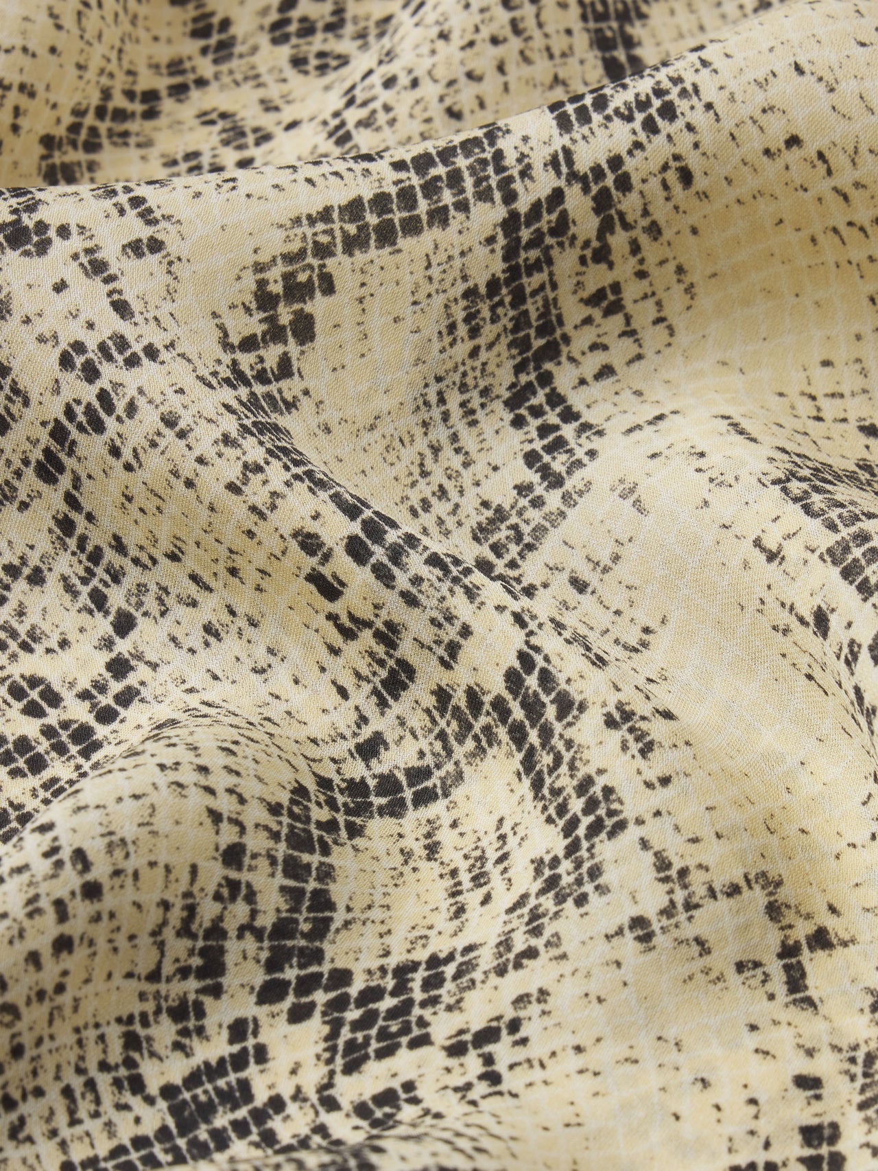 Close-up of fabric with black snake skin pattern on beige background