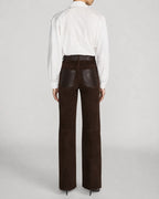 A model shown from the back wearing dark brown wide-leg trousers with dark brown leather patch pockets and a white button-down shirt, set against a light gray studio background.