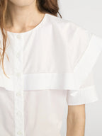 White blouse with short sleeves worn by a person, close-up on the chest and shoulders.