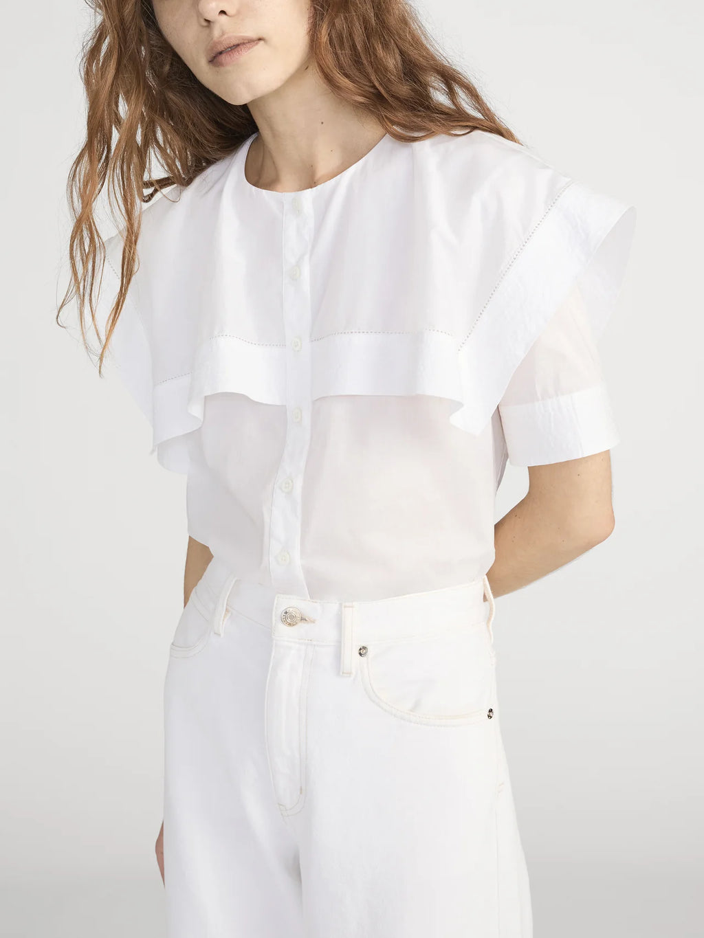 Person wearing a white outfit with sheer panels on a plain background