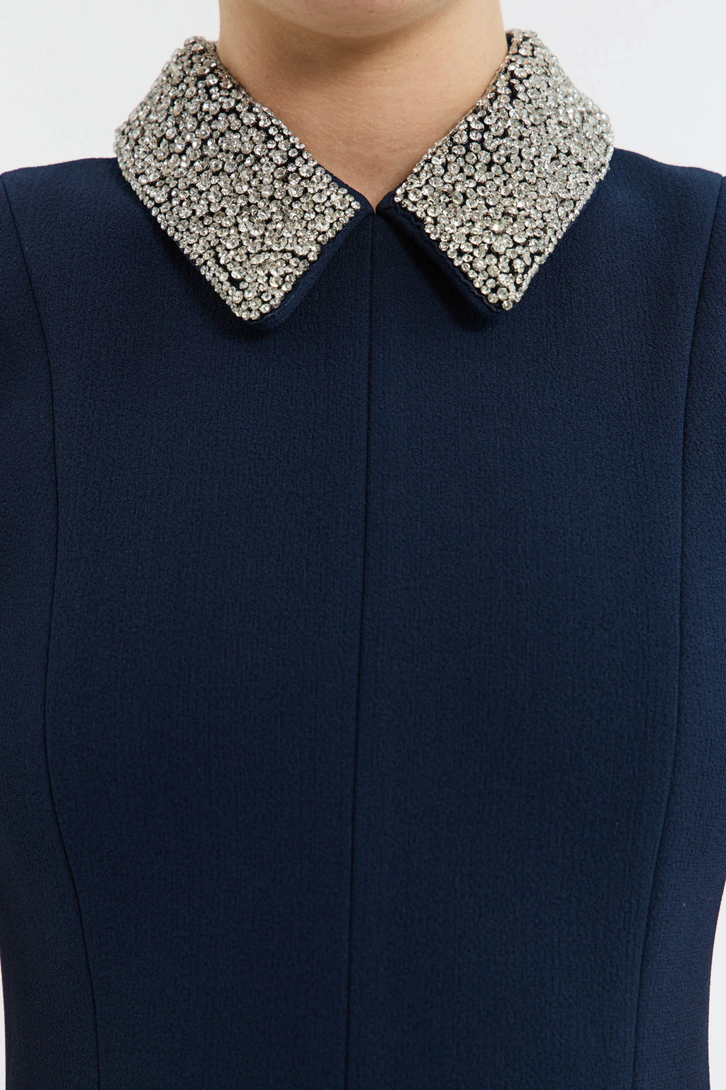Navy blue dress with a decorative silver collar on a white background
