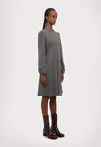 Woman wearing a gray dress with brown boots on a white background