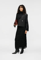 Woman wearing a black outfit with a feathered skirt on a white background