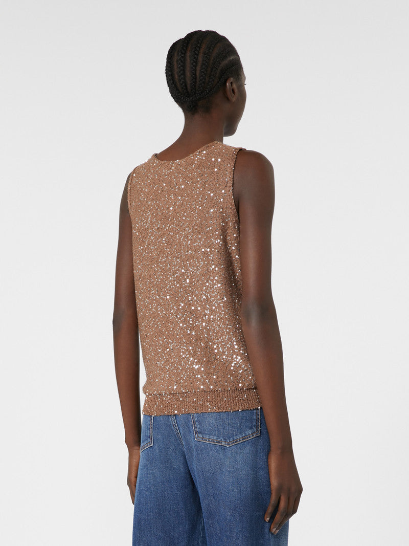 Person wearing a sparkly brown top and blue jeans on a white background