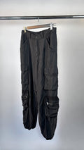 Black cargo pants hanging on a rack against a white background