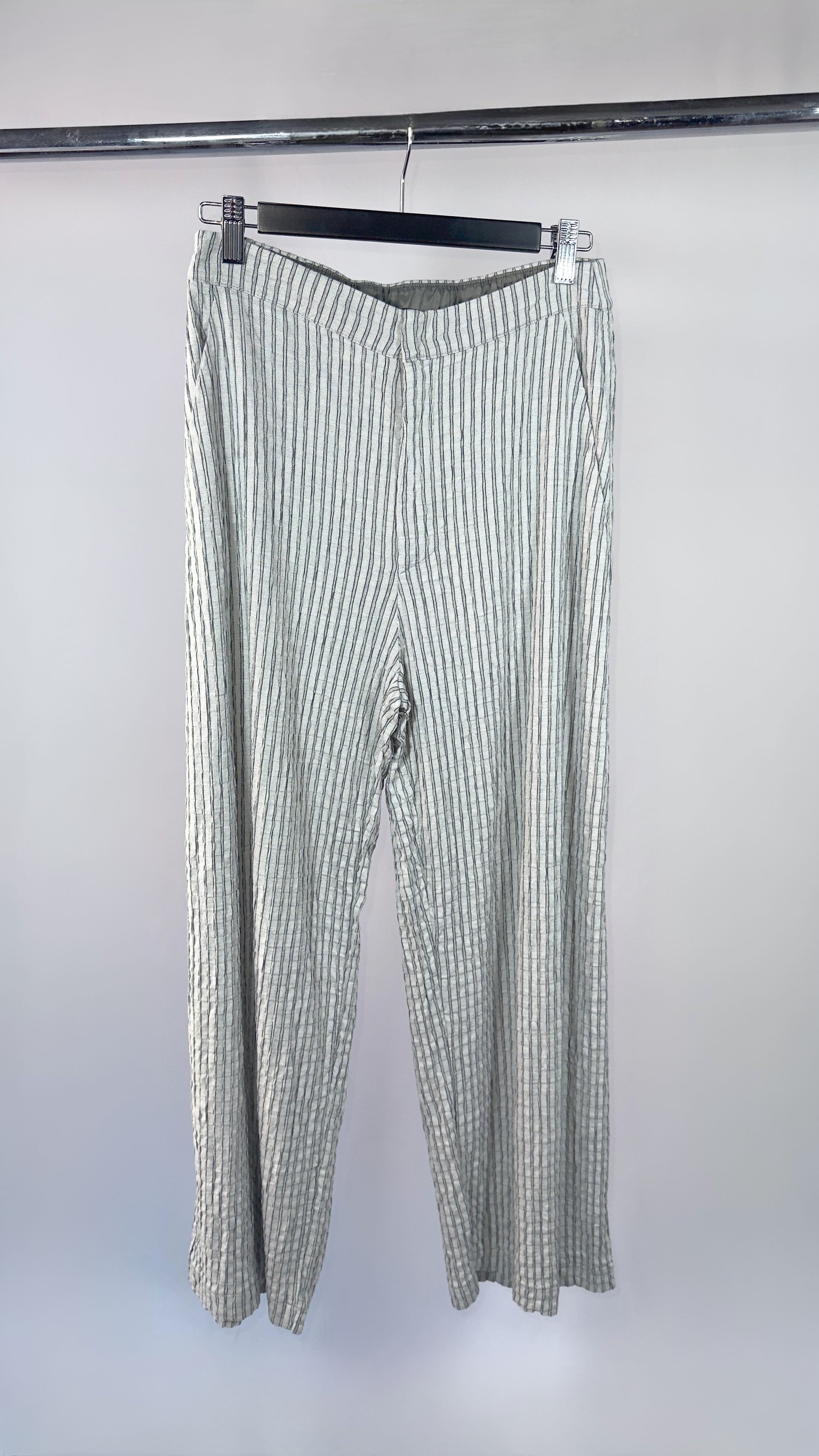 Striped pants hanging on a rack against a white background