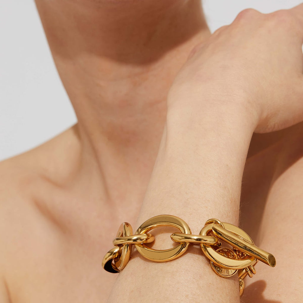 Gold chain bracelet on a person's wrist with a neutral background