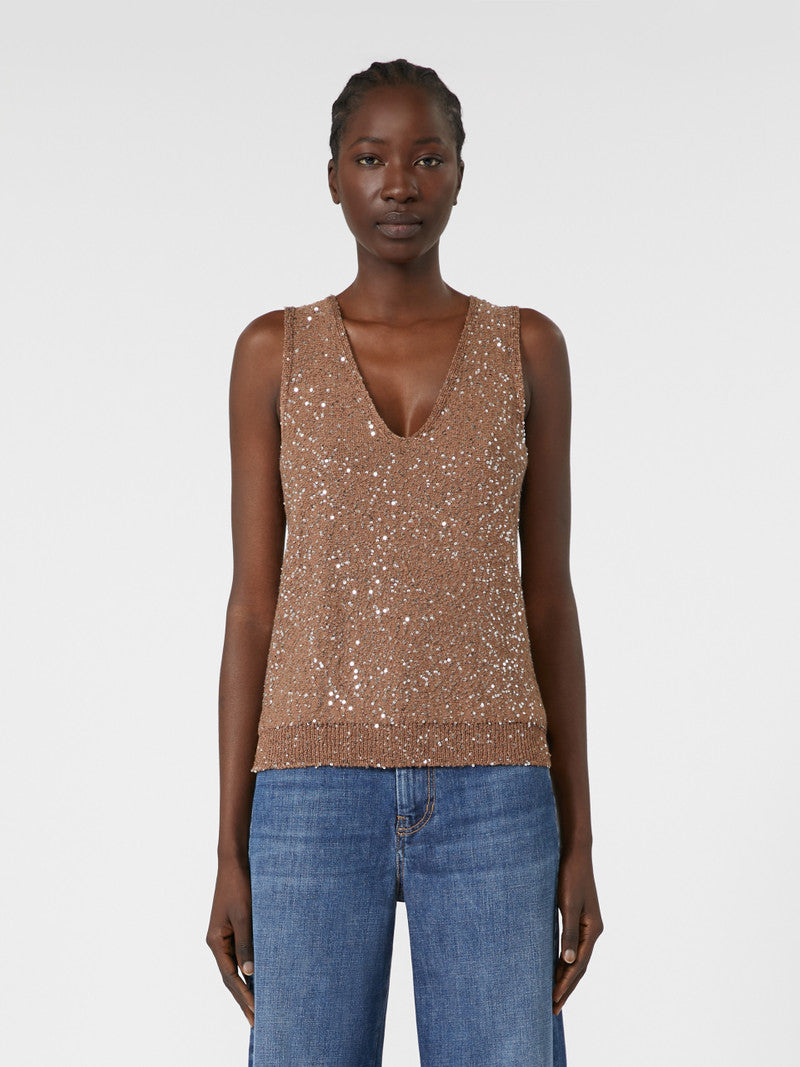 Woman wearing a sparkly brown top and blue jeans on a white background