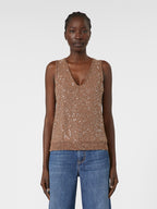 Woman wearing a sparkly brown top and blue jeans on a white background