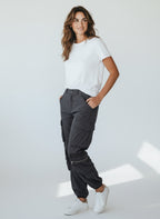 Woman wearing a white t-shirt and dark gray jogger pants on a white background