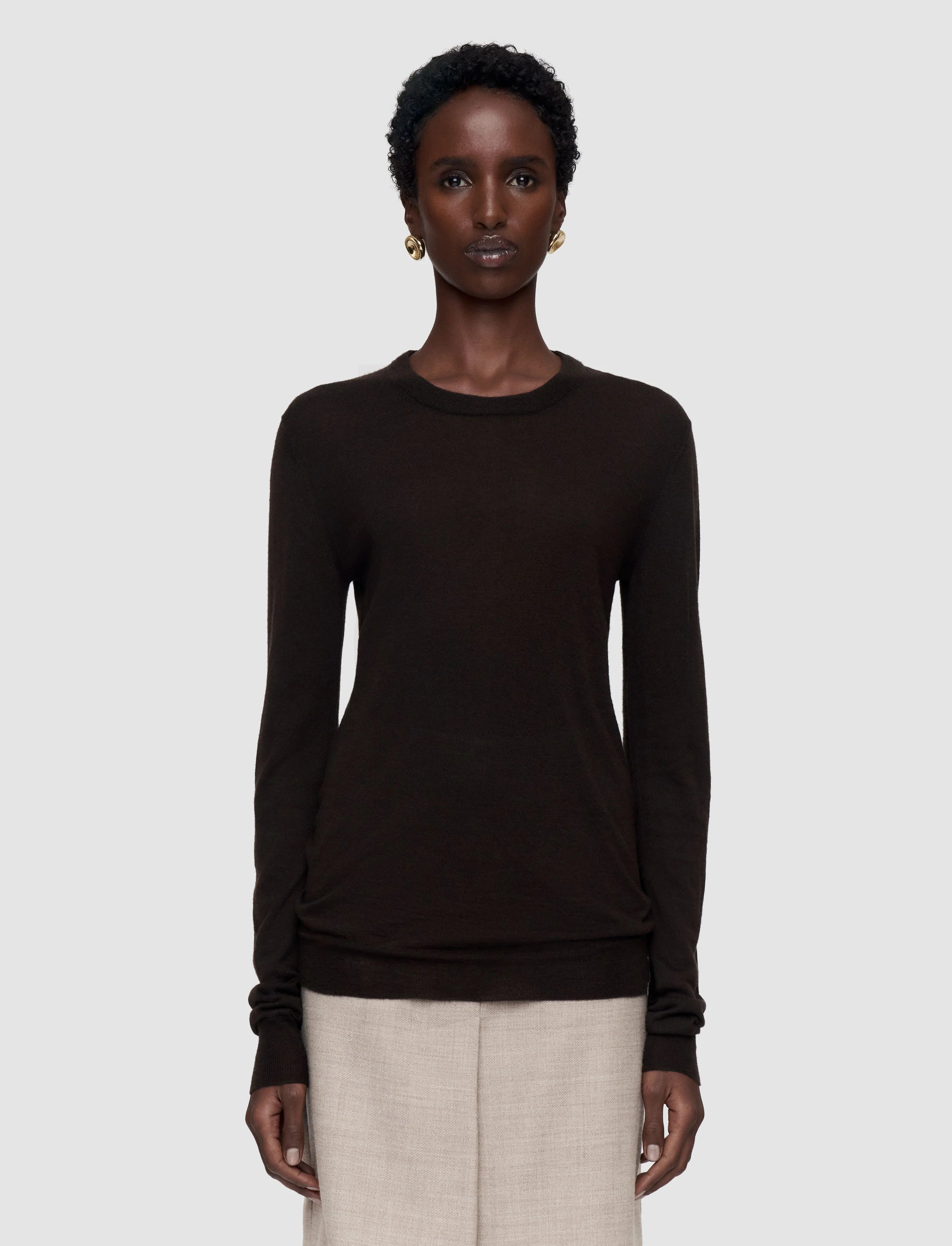 Woman wearing a cocoa brown sheer long-sleeve top and beige skirt on a white background by Joseph 