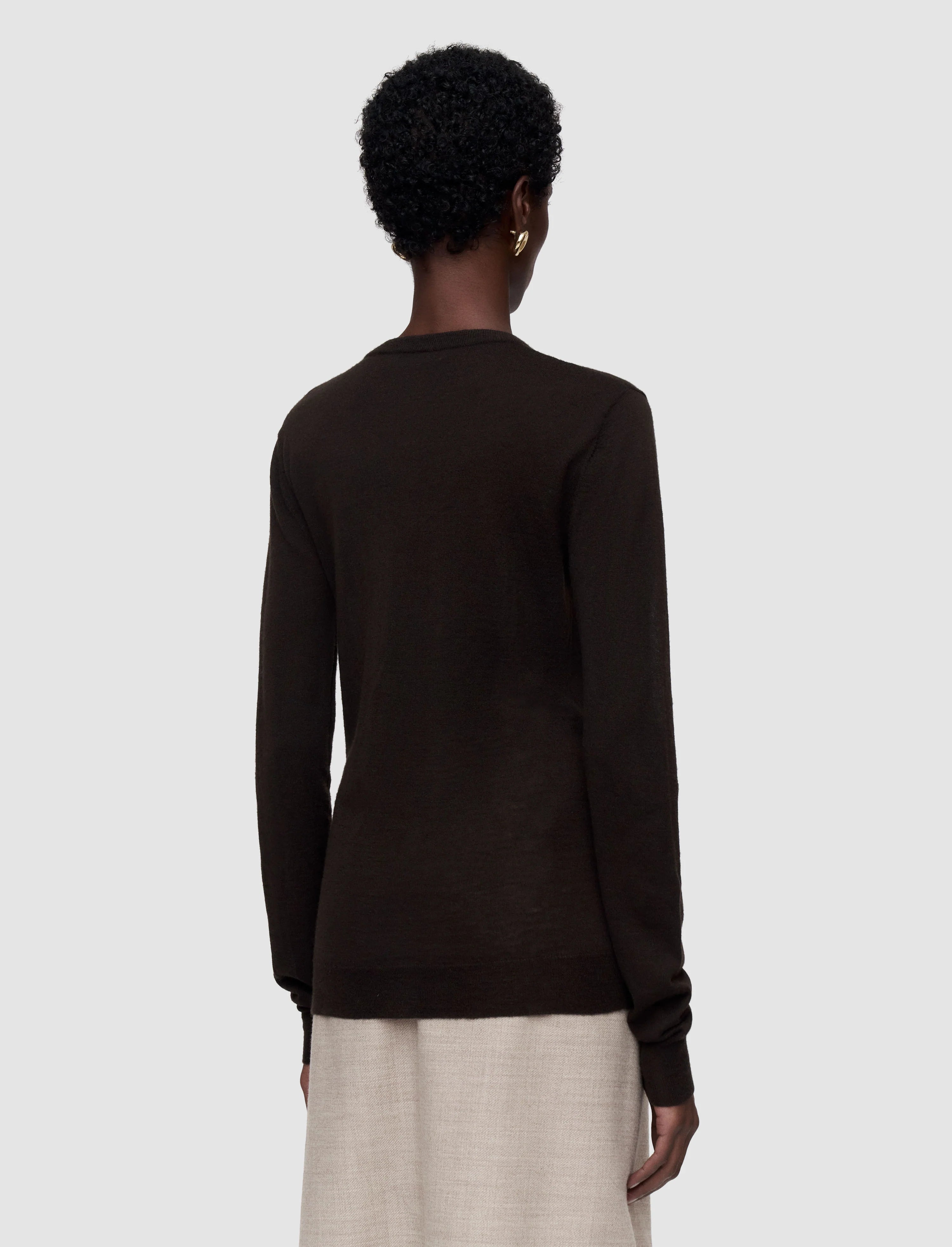 Person wearing a dark brown sweater on a light gray background Joseph 