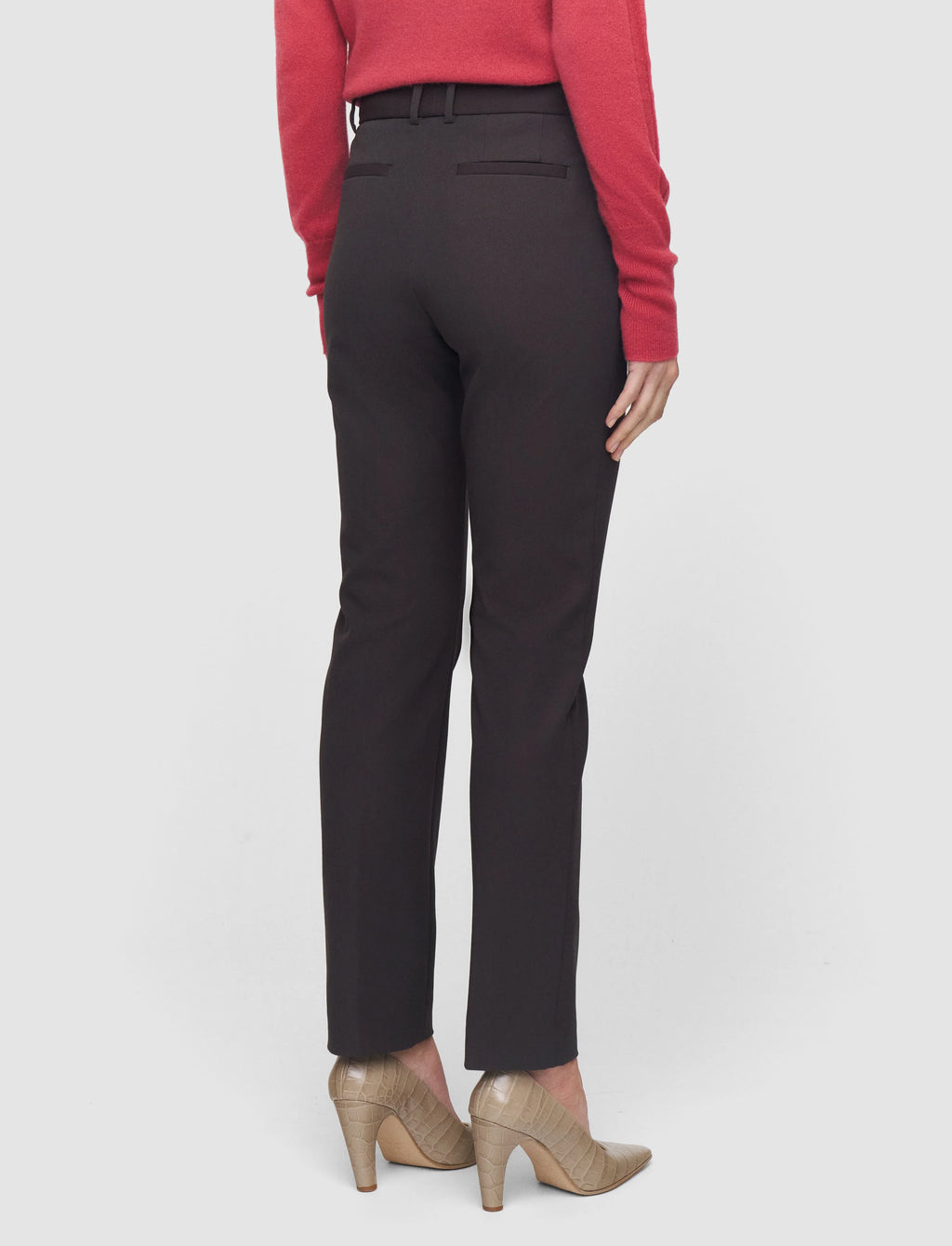 Person wearing chocolate brown pants and a red top on a white background