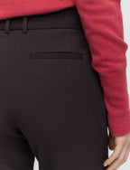 Close-up of dark brown pants with a red sweater sleeve in the background