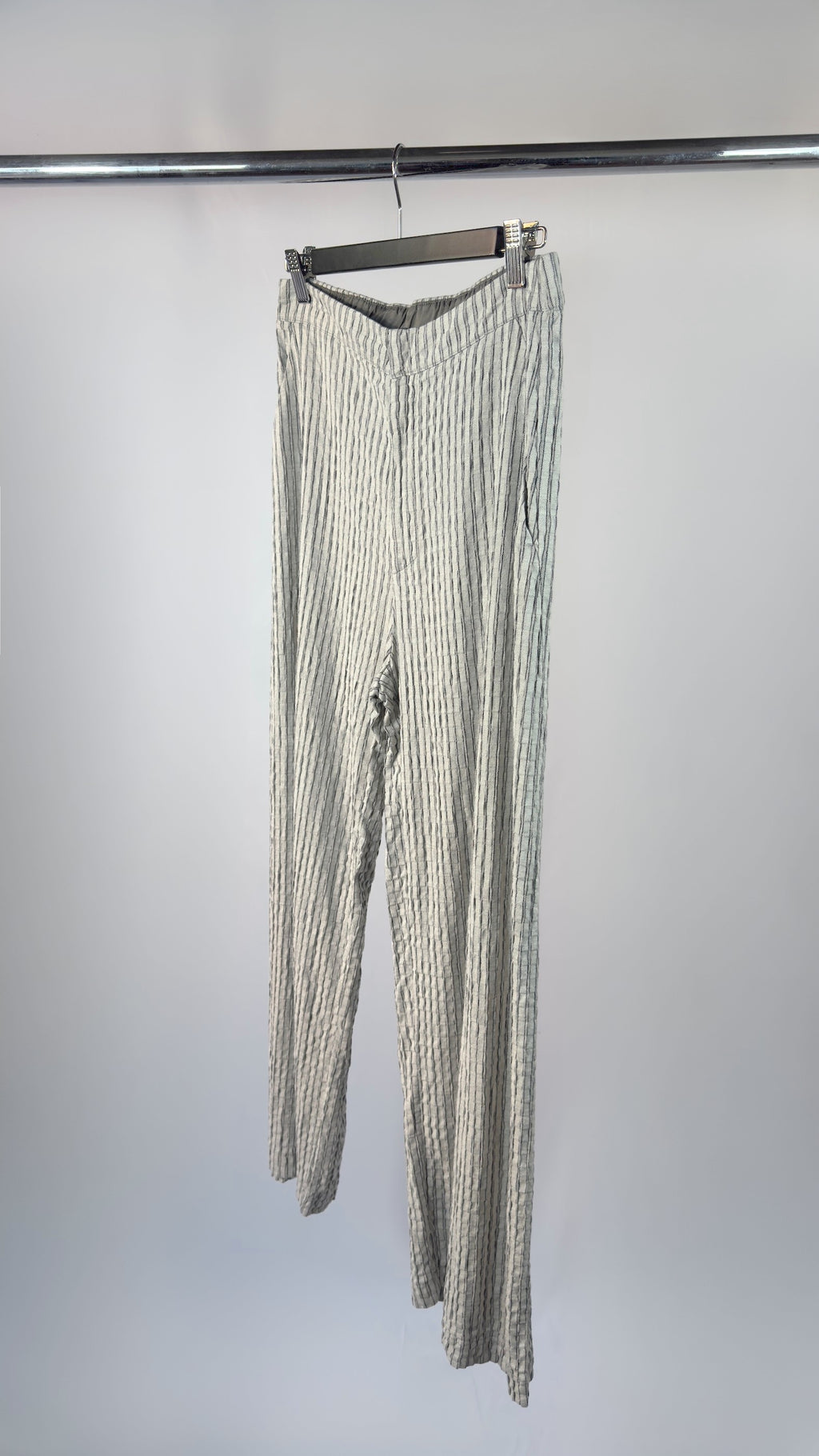 Striped pants hanging on a rack against a white background