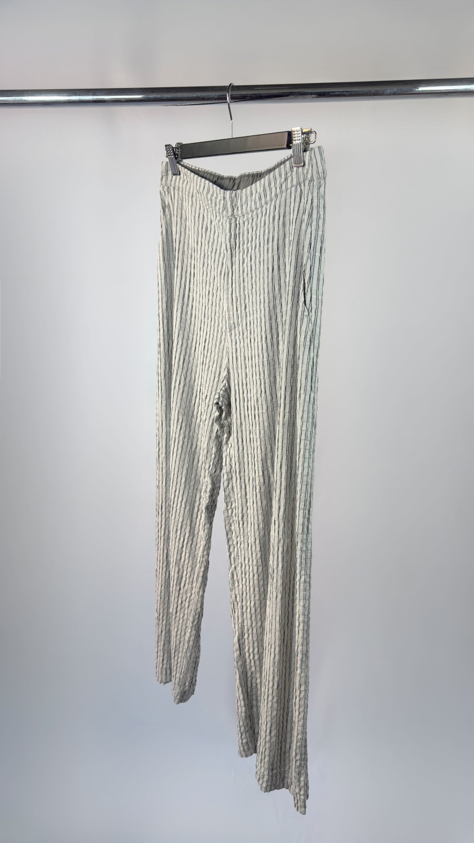 Striped pants hanging on a rack against a white background