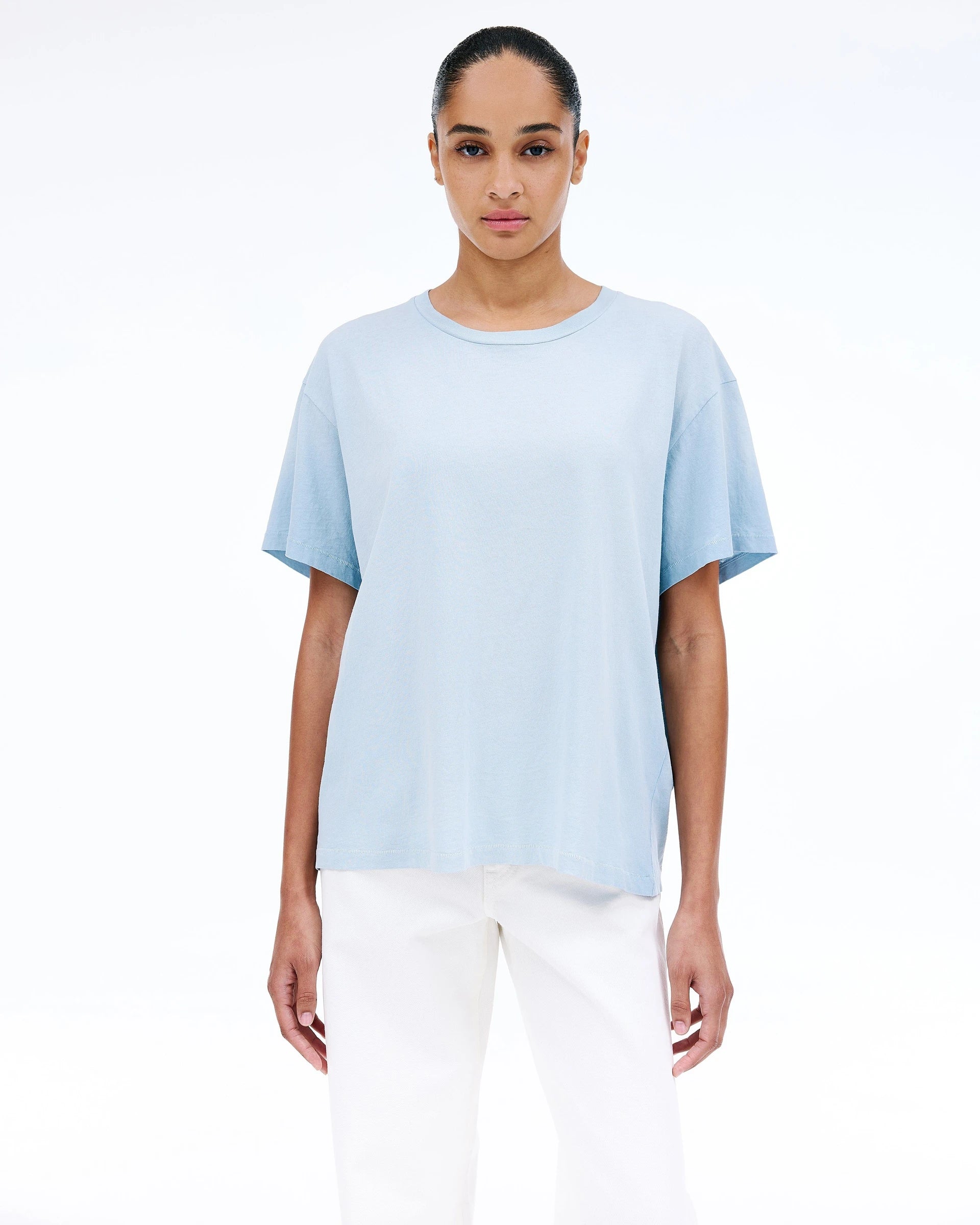 Woman wearing a light Sllvrlake blue t-shirt and white pants on a white background shop online muse boutique hawthorn
