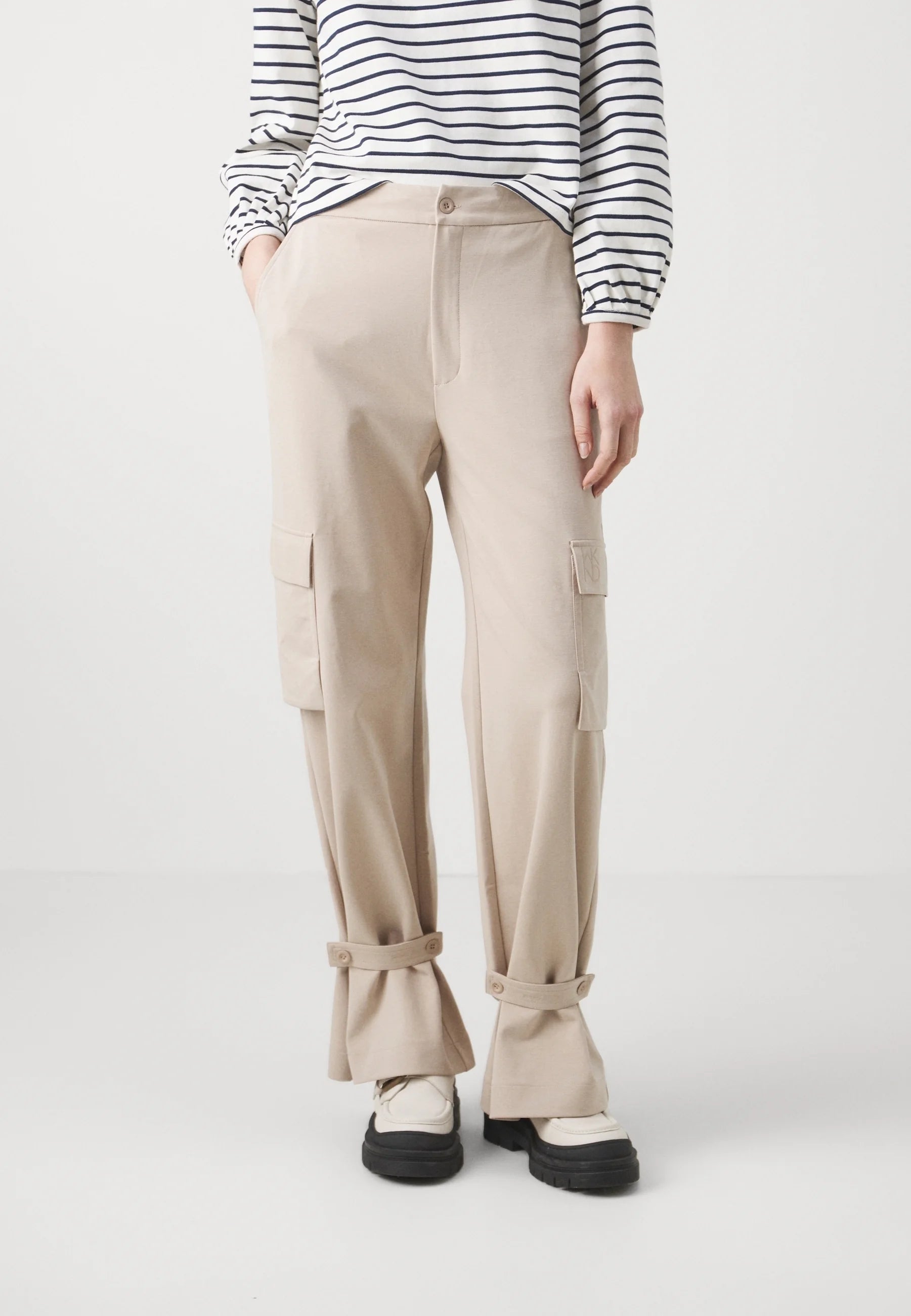 Person wearing beige cargo pants and a striped shirt on a white background