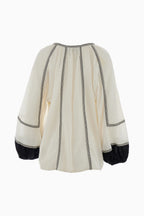 White blouse with black trim on a white background