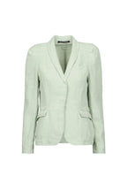 A light sage green tailored blazer by Hannes roether with a shawl collar, structured shoulders, and flap pockets, shown on a plain light blue background.