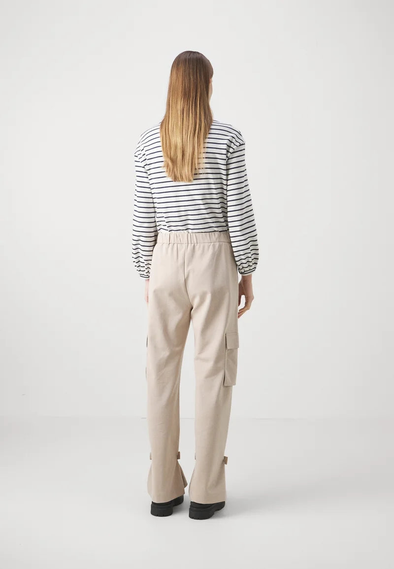 Person wearing a striped shirt and beige pants on a white background