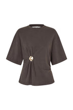 A dark brown short-sleeve knit top with a gathered twist detail at the center front, secured by a prominent gold-tone button, shown on a plain white background.