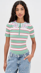 Woman wearing a green and pink striped shirt with floral details on a white background