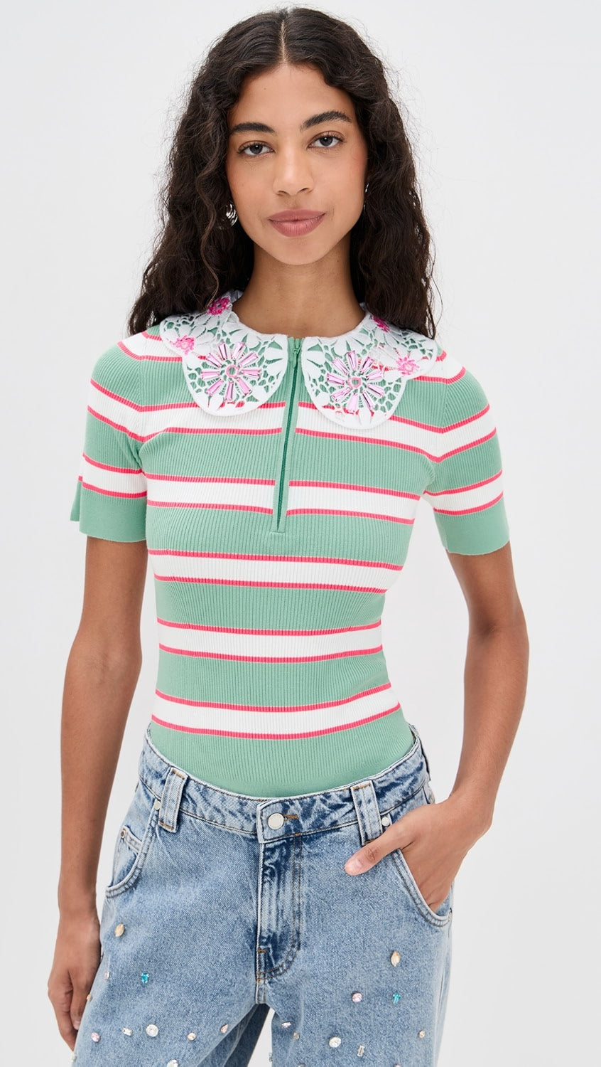 Woman wearing a green and pink striped shirt with floral details on a white background
