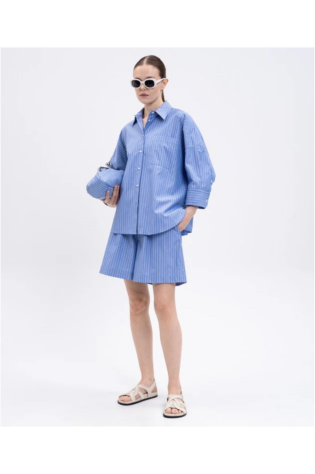 Person wearing a blue checkered outfit with sunglasses on a white background