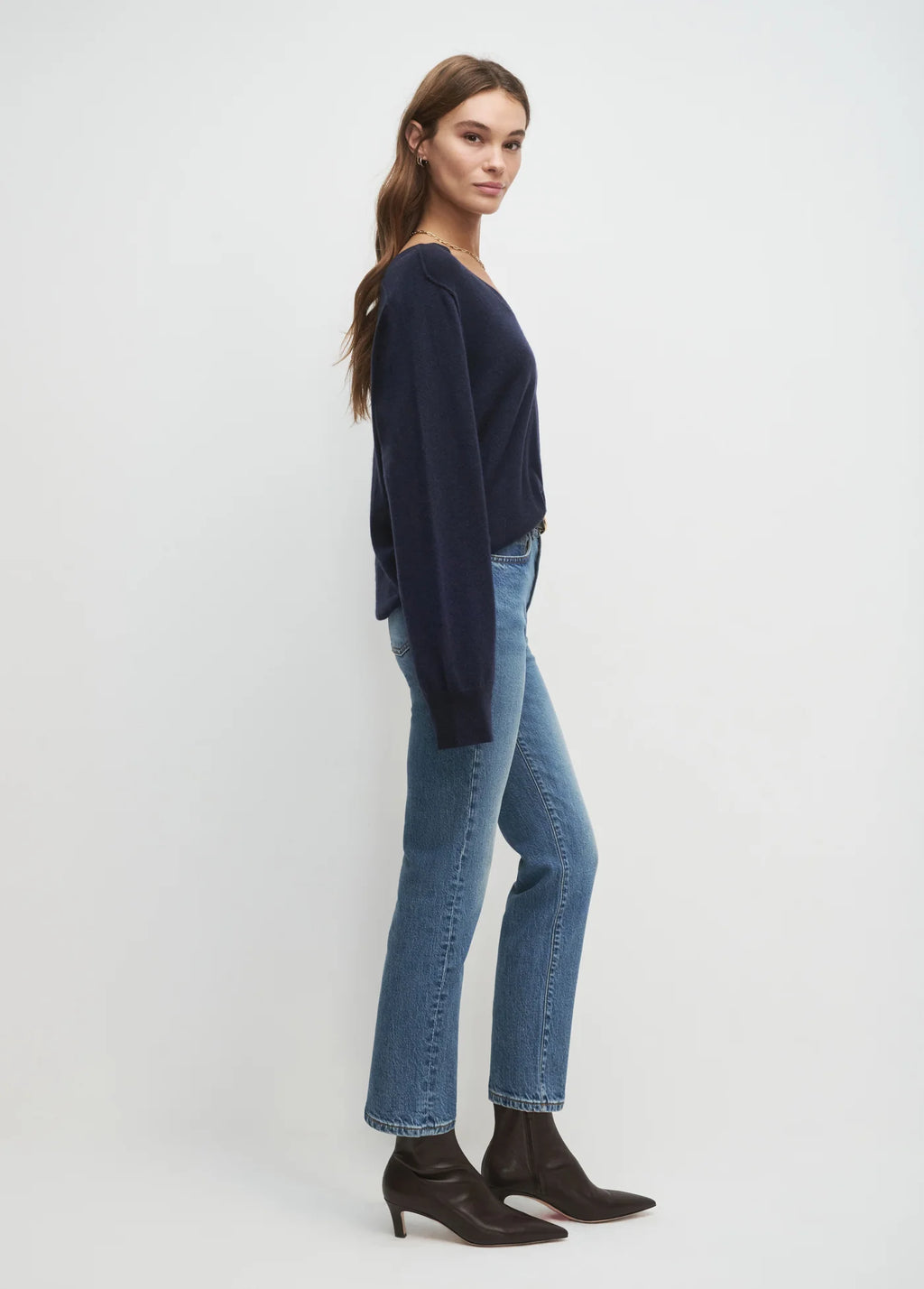 Woman wearing a navy sweater and blue jeans on a white background