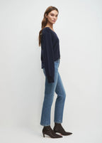 Woman wearing a navy sweater and blue jeans on a white background