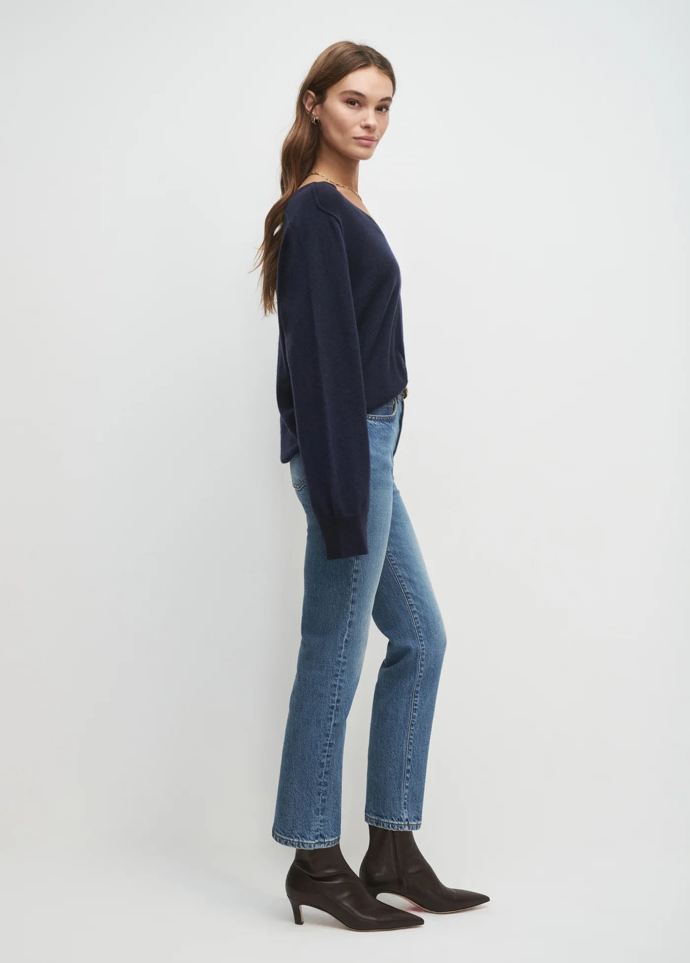 Woman wearing a navy sweater and blue jeans on a white background