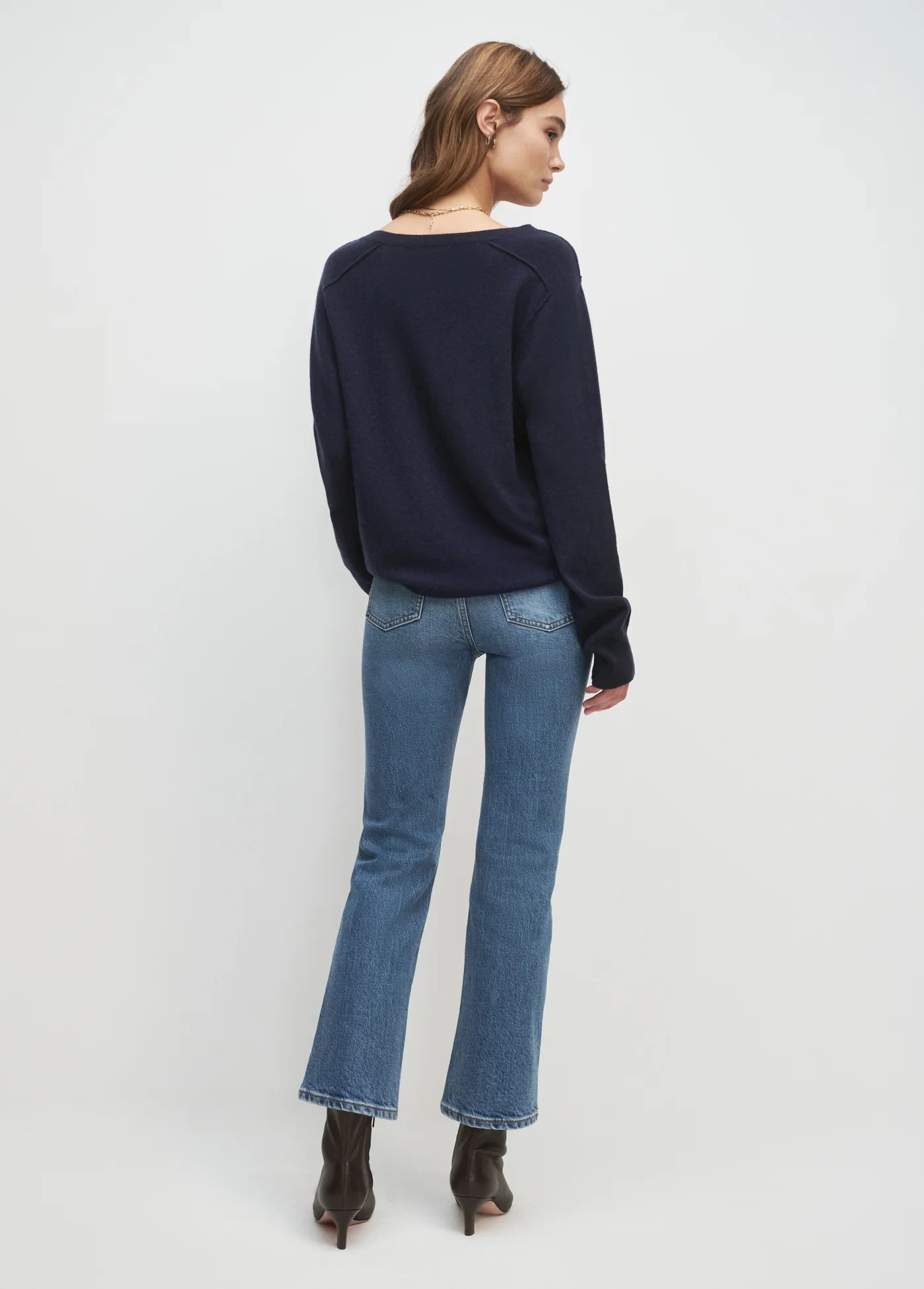 Woman wearing a navy sweater and blue jeans on a white background