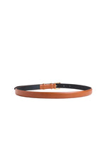 A slim leather belt in a warm tan/cognac brown color, shown coiled on a light beige background. The underside of the belt is black, and it features a small gold-tone metal buckle.