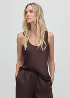 Woman wearing a brown sleeveless top and pants on a light gray background