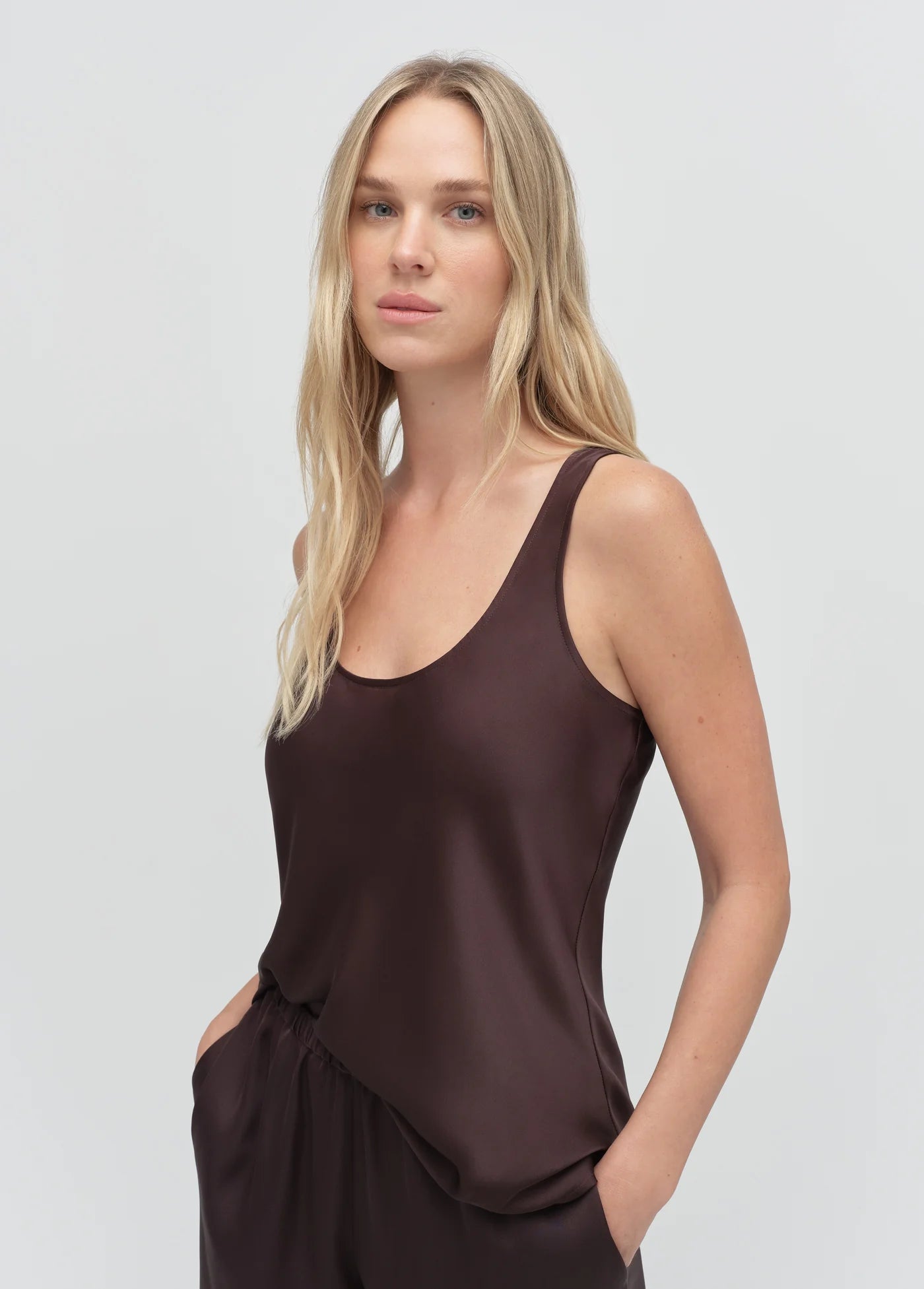 Woman wearing a brown sleeveless top against a plain background