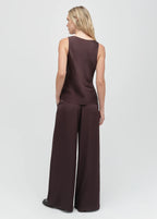 Woman wearing a brown sleeveless top and wide-leg pants on a white background