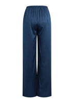A pair of wide-leg trousers in a deep navy blue satin fabric, shown from the back against a solid light beige background.