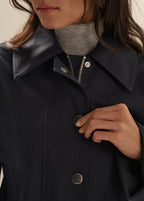 Person wearing a dark coat with buttons, focusing on the collar and buttons.