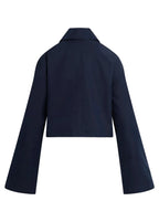 A cropped navy blue blazer with long wide sleeves, shown from the back against a solid light beige background.