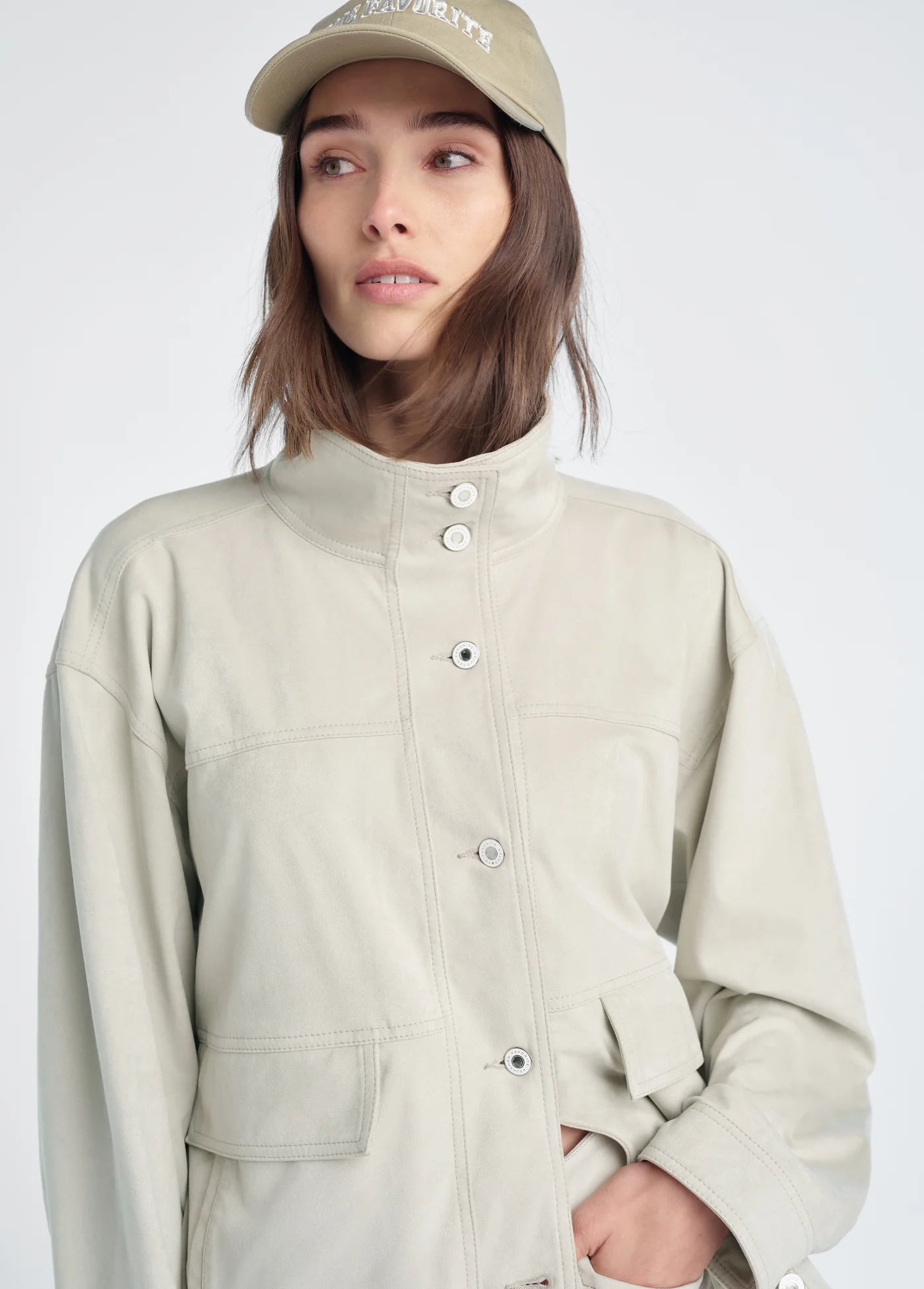 Person wearing a beige jacket and cap on a white background