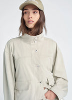 Person wearing a beige jacket and cap on a white background
